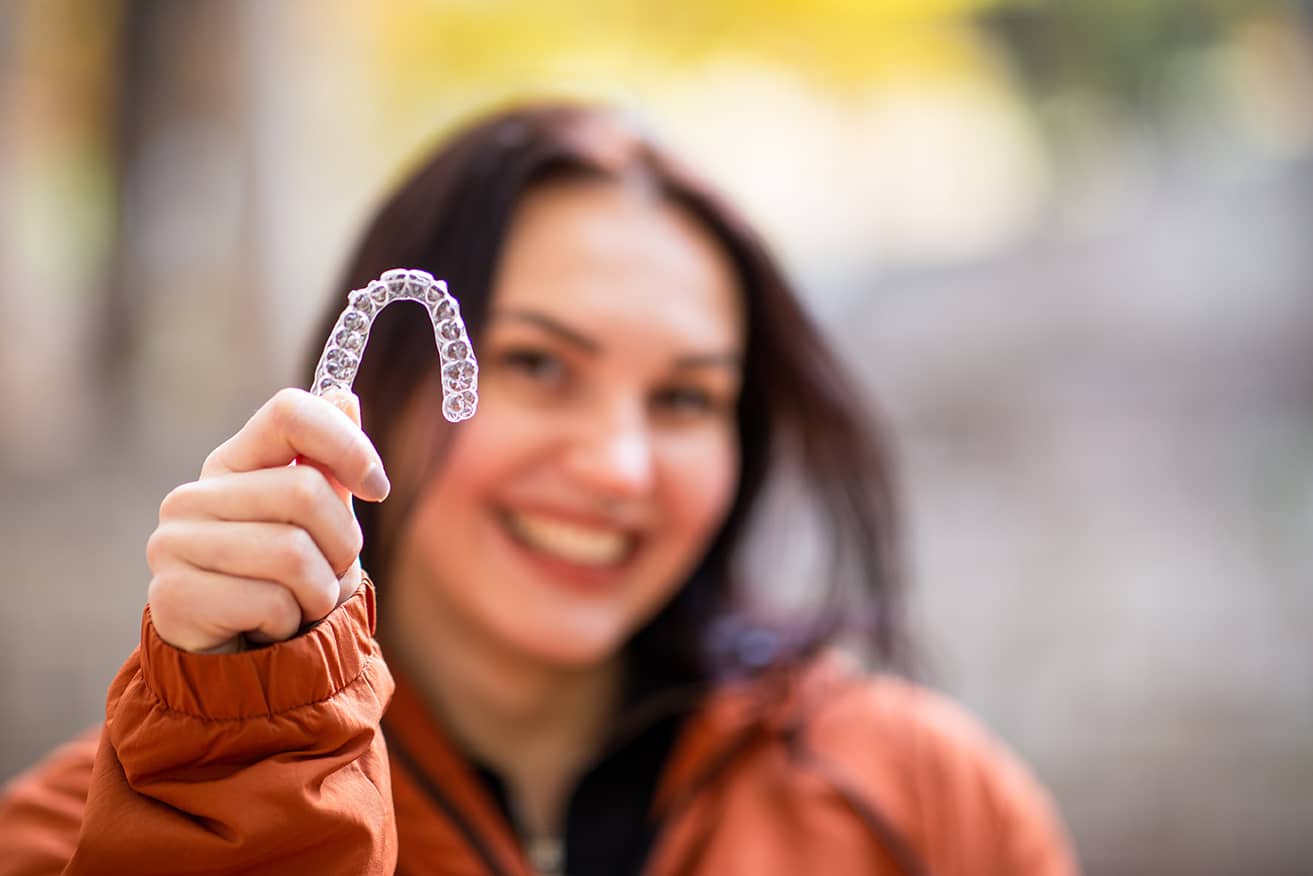 girl holding up a clear dental aligner tray at prosper dental studio in cornelius nc